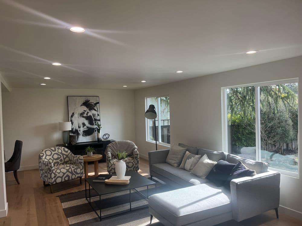 Modern living room with gray sofa, patterned chairs, and large windows for natural light.